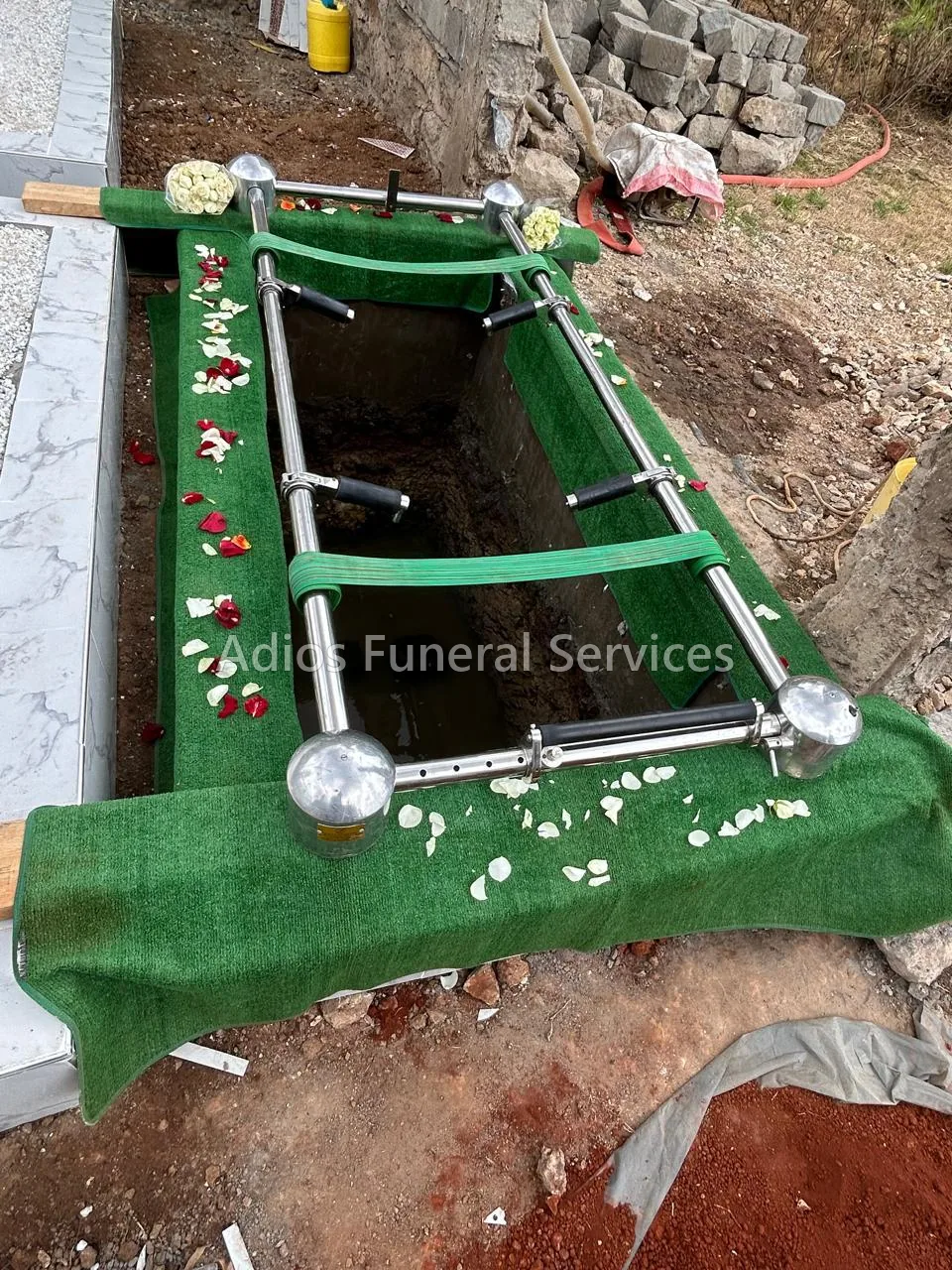 Lowering gear and artificial grass set up over a grave by Adios Funeral Services